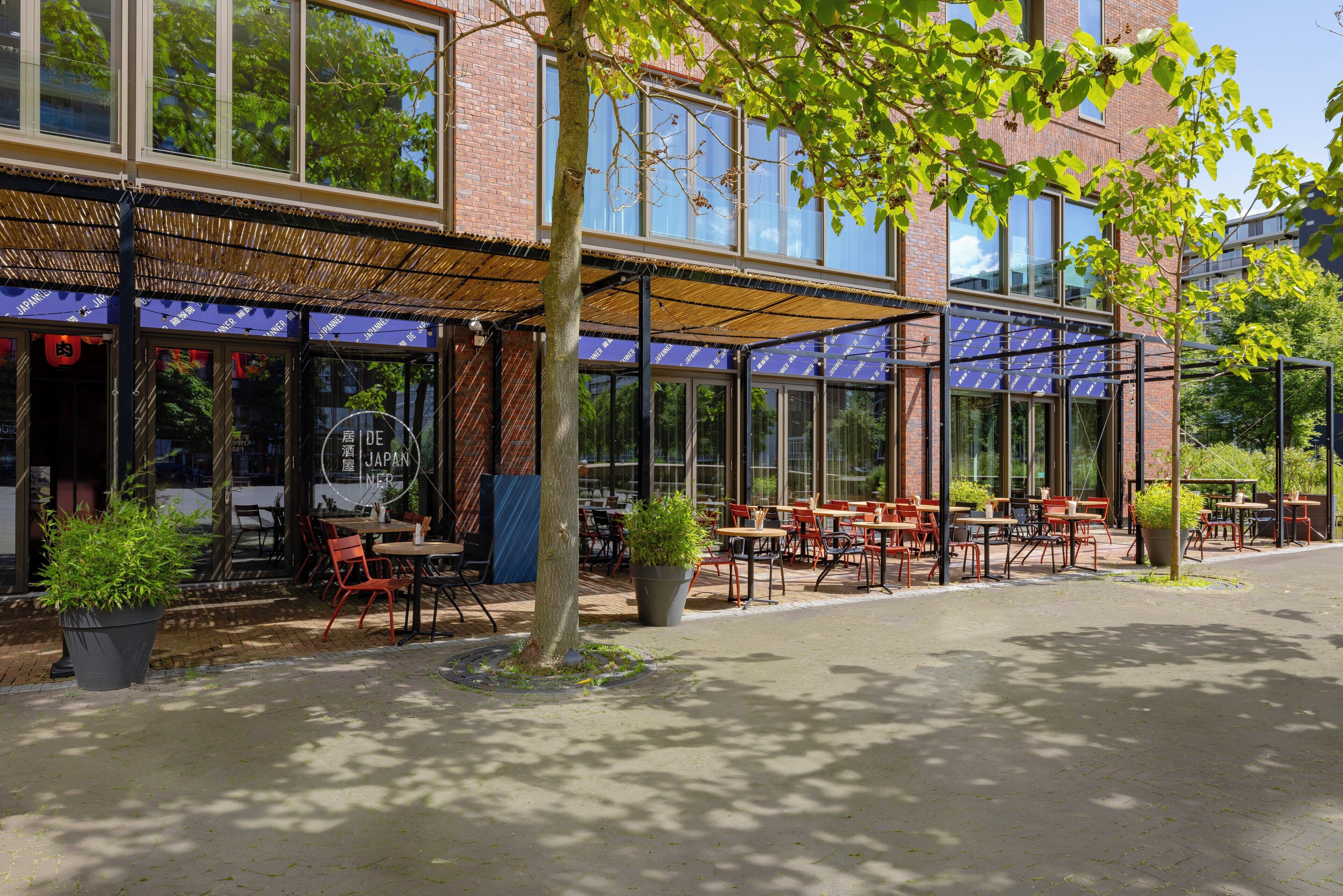 A restaurant with outdoor seating, large windows, and a brick facade.