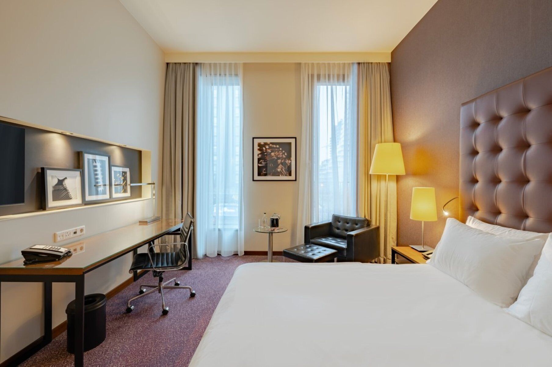 Habitación de hotel con una cama grande, un escritorio con una silla, una mesita pequeña, un sofá y un cabecero.