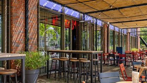 An outdoor seating area with tables and chairs, a potted plant, and a brick wall. - Crowne Plaza Amsterdam South by IHG (Amsterdam)