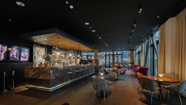 A modern bar area with a marble counter, multiple seating options, and large windows providing natural light. - Crowne Plaza Amsterdam South by IHG (Amsterdam)