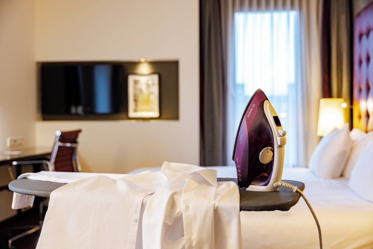 Une chambre d’hôtel équipée d’une planche à repasser, d’un fer à repasser et d’un lit.