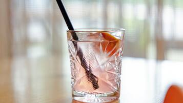 A clear glass with a black straw and an orange slice, placed on a wooden surface.