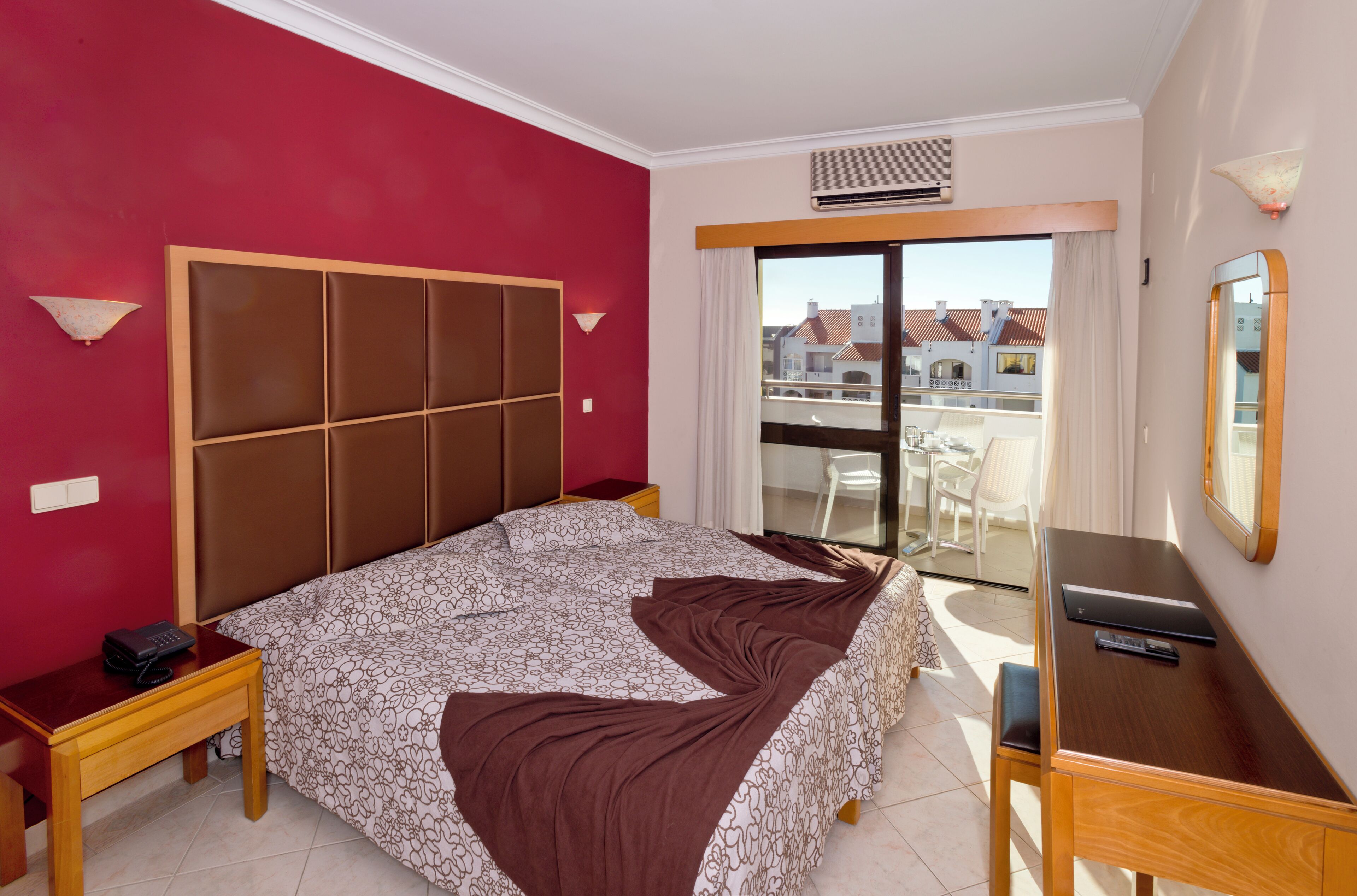Une chambre d’hôtel avec un grand lit, un bureau, une chaise, un téléphone et une vue sur l’extérieur.