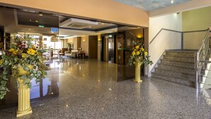 A hotel lobby with polished granite floors, a staircase, and two large flower arrangements. - Paladim & Alagoamar Hotels (Albufeira)