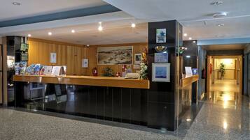 A reception area with a counter, informational posters, a fire extinguisher, and a corridor leading to other areas.