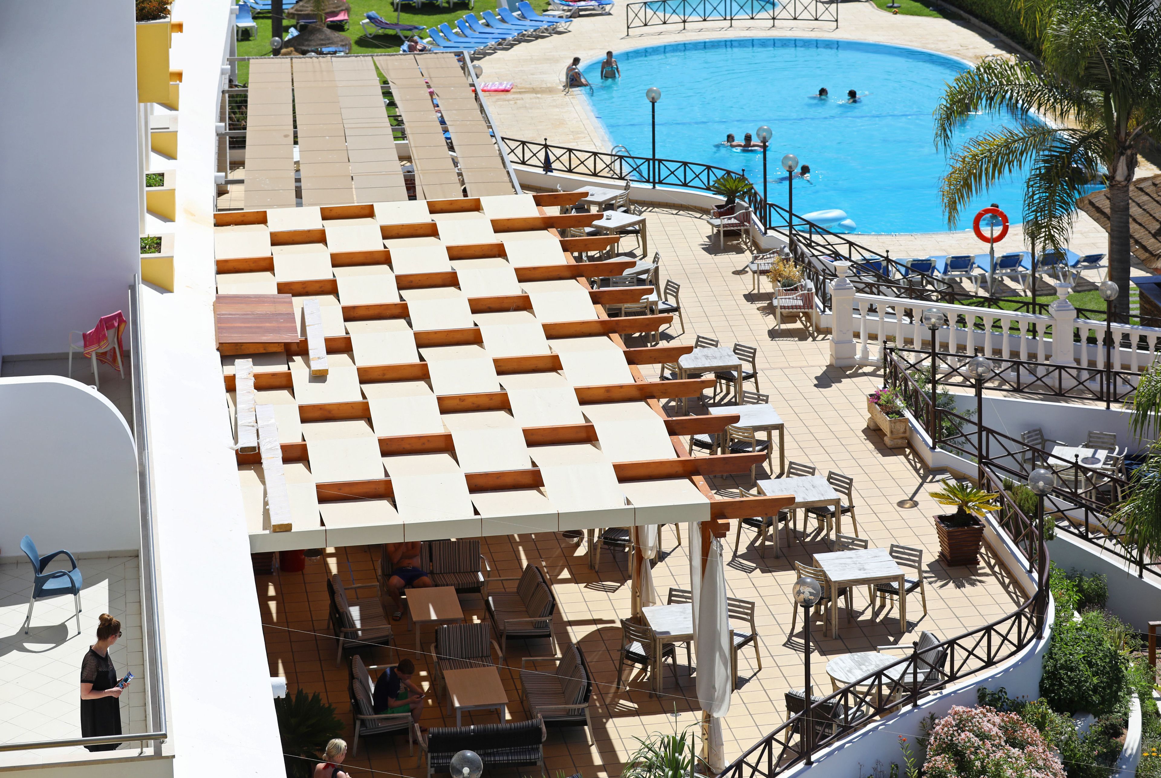 A rooftop pool area with lounge chairs and tables, a swimming pool, and a view of the beach.