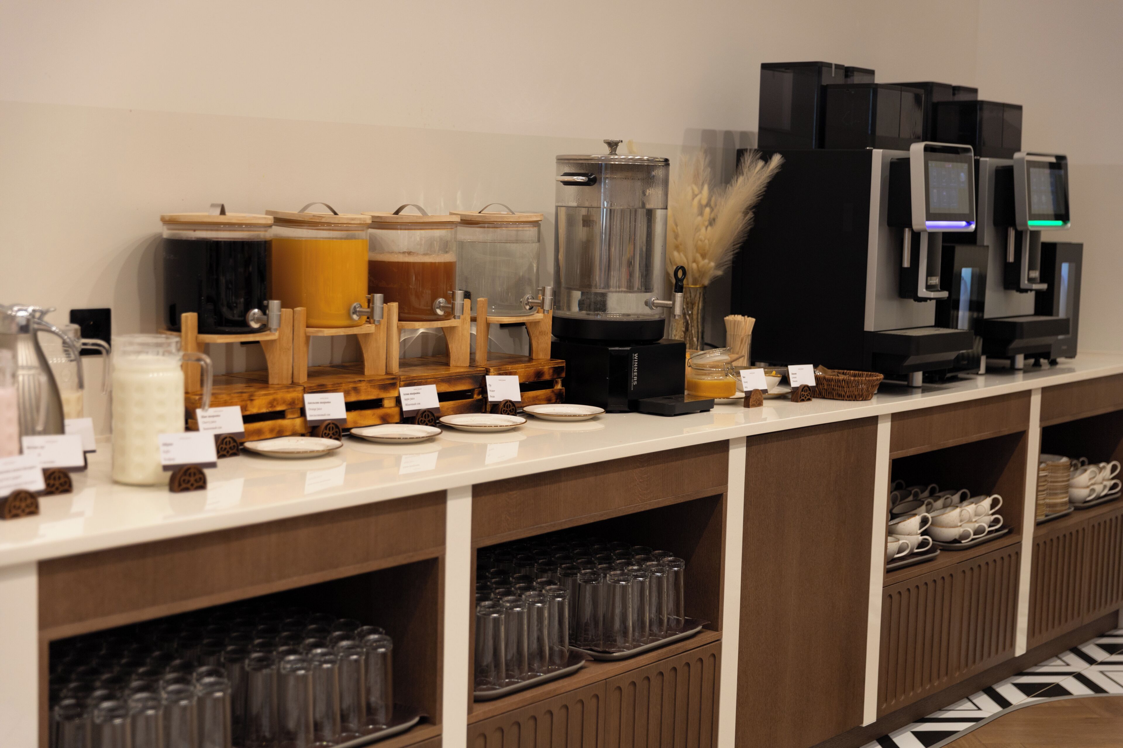 Montaje tipo bufé con distintas estaciones de comida y bebida, incluyendo una cafetera y un dispensador de líquidos.