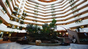 A multi-level atrium with a central garden, multiple balconies with plants, and a dome structure. - Rahat Palace Hotel (Almaty)