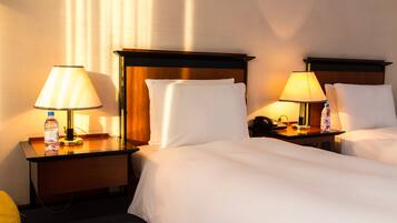 A hotel room with two beds, nightstands, lamps, a water bottle, and a phone.