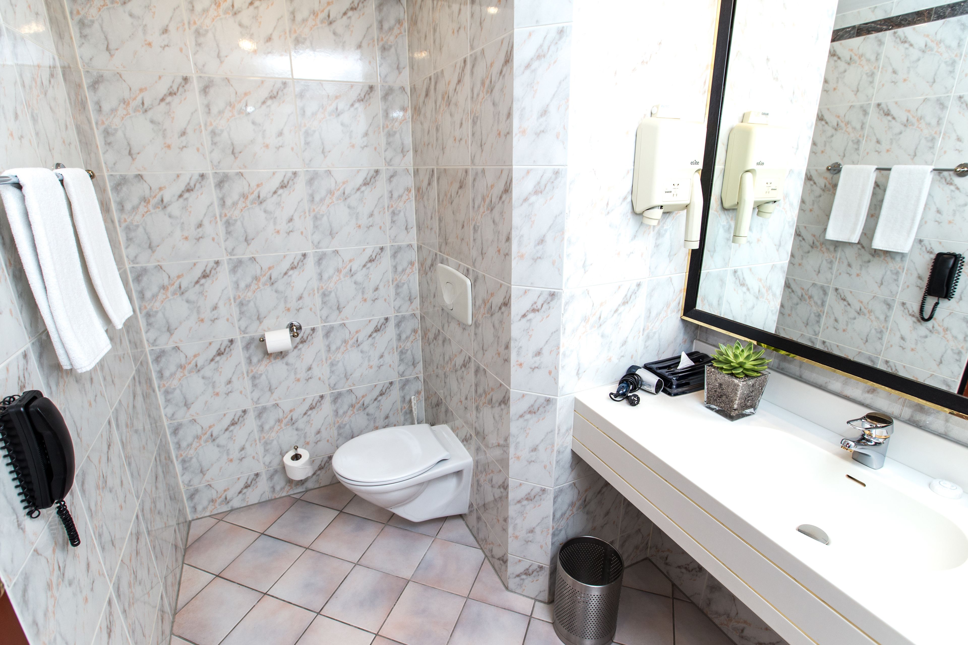 A bathroom with a toilet, sink, mirror, and towel rack.