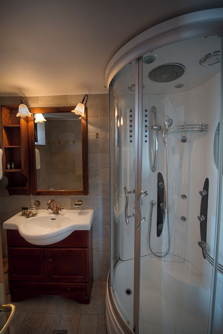 Un baño con ducha envuelta en vidrio curvo, tocador con lavabo y espejo.
