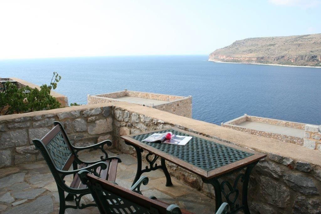 Un patio de piedra con una mesa y sillas con vistas al mar.