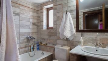 Un baño con bañera, inodoro, lavabo y ventana.