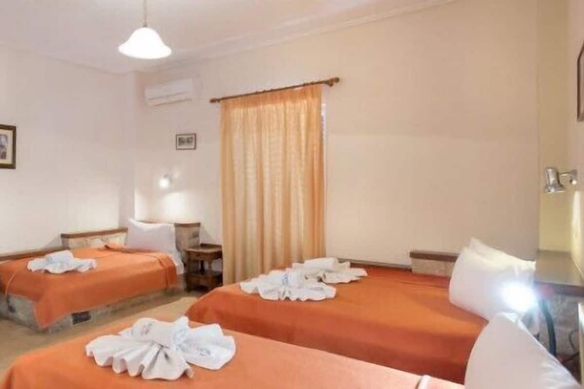 Quarto de hotel com duas camas, uma escrivaninha, uma cadeira, uma televisão e um abajur.