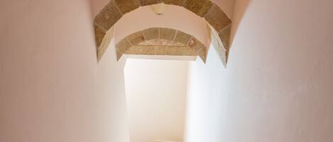A staircase with a stone archway leading to a bright room.