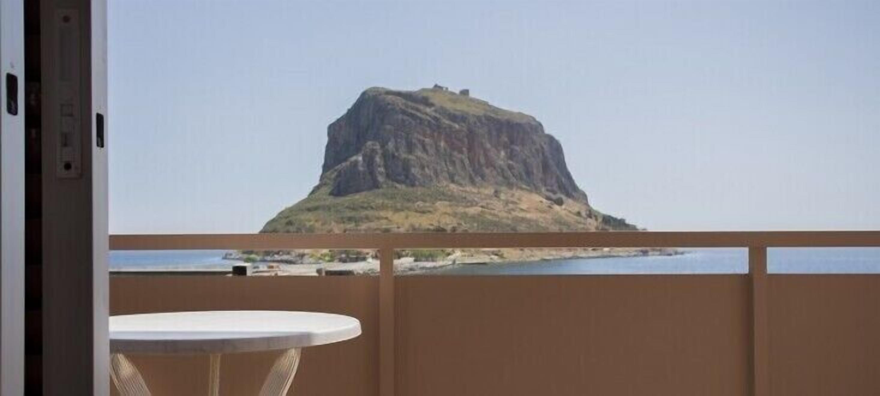 Un balcon donnant sur une colline rocheuse et un plan d’eau.
