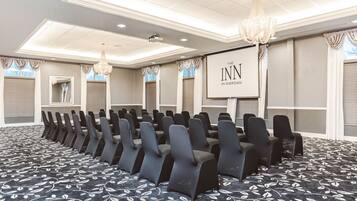 A conference room with rows of chairs, a projector screen, and a carpet with a leaf pattern.