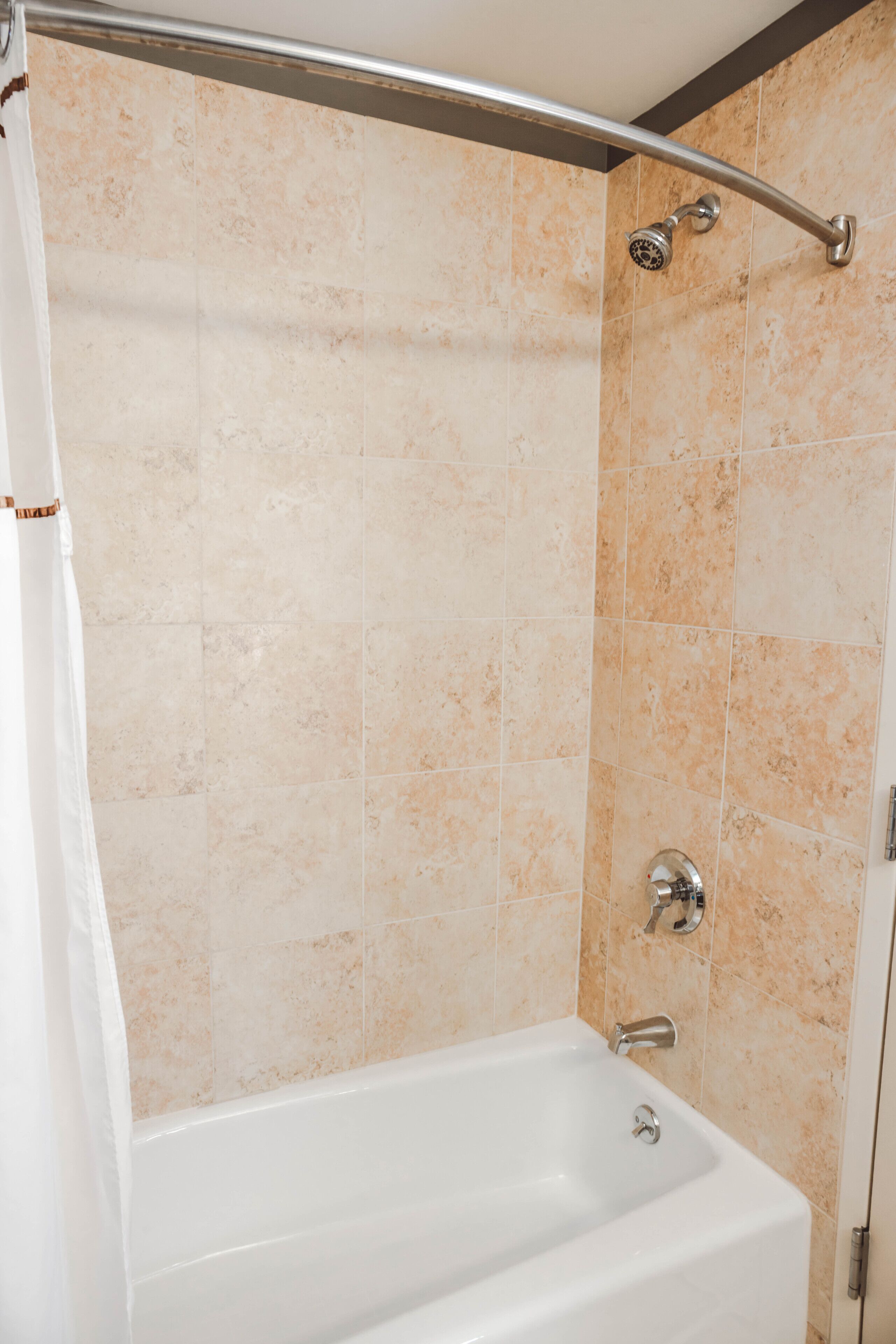 A bathroom with a bathtub, shower, and tiled walls.