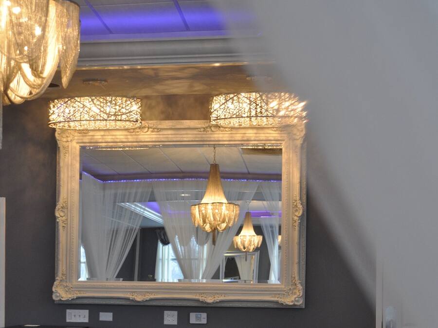 A bar area with a tufted backrest, two barstools, a mirror, and a chandelier.