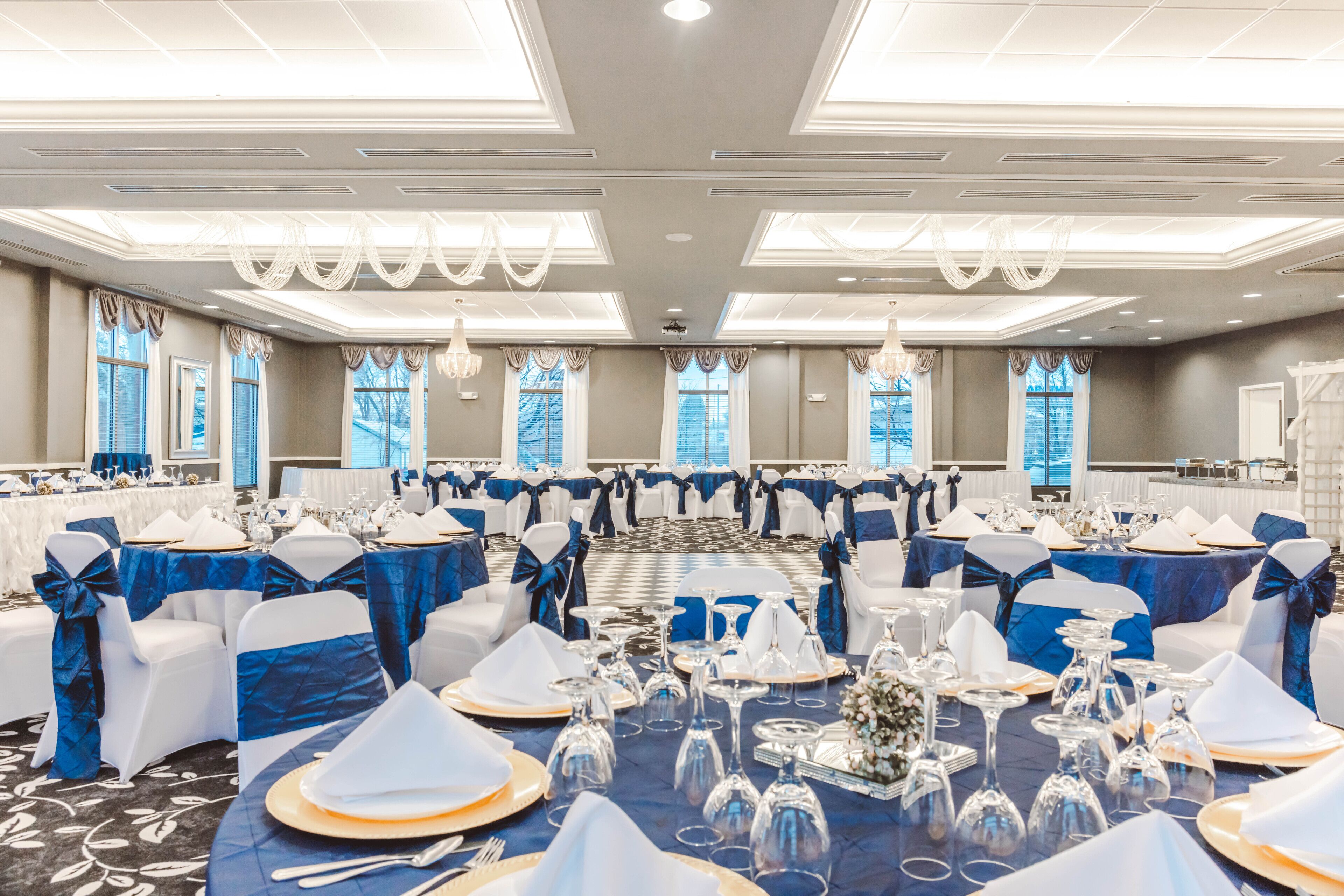 A banquet hall with round tables set for a formal event, featuring blue and white decor.