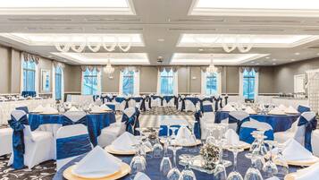 A banquet hall with round tables set for a formal event, featuring blue and white decor.