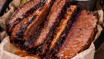 Una cesta de costillas a la parrilla con pepinillos y salsa.