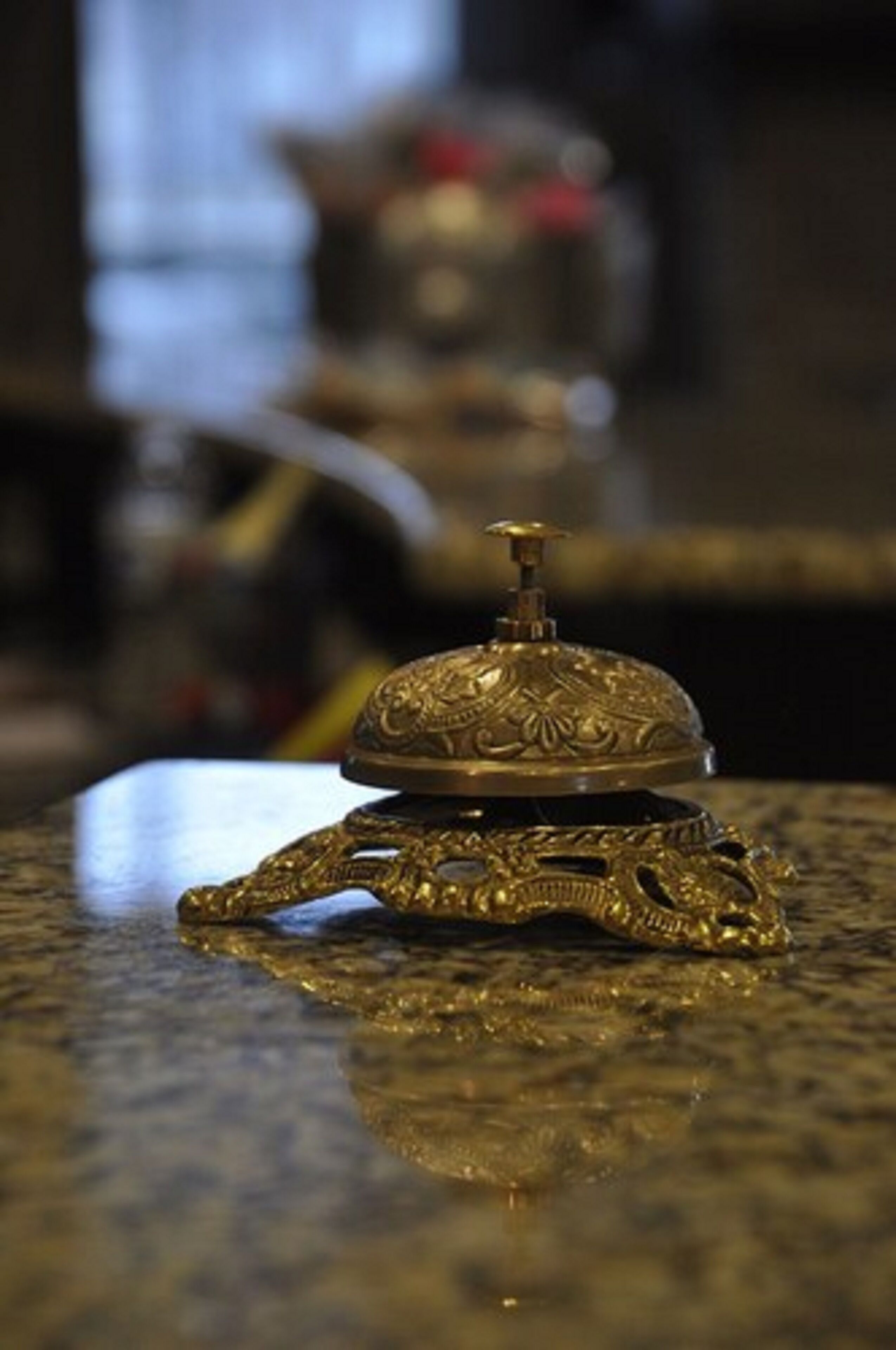 A small, ornate brass object with intricate designs, placed on a reflective surface.