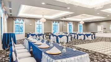 A banquet hall with tables set for events, featuring a checkered floor and large windows.
