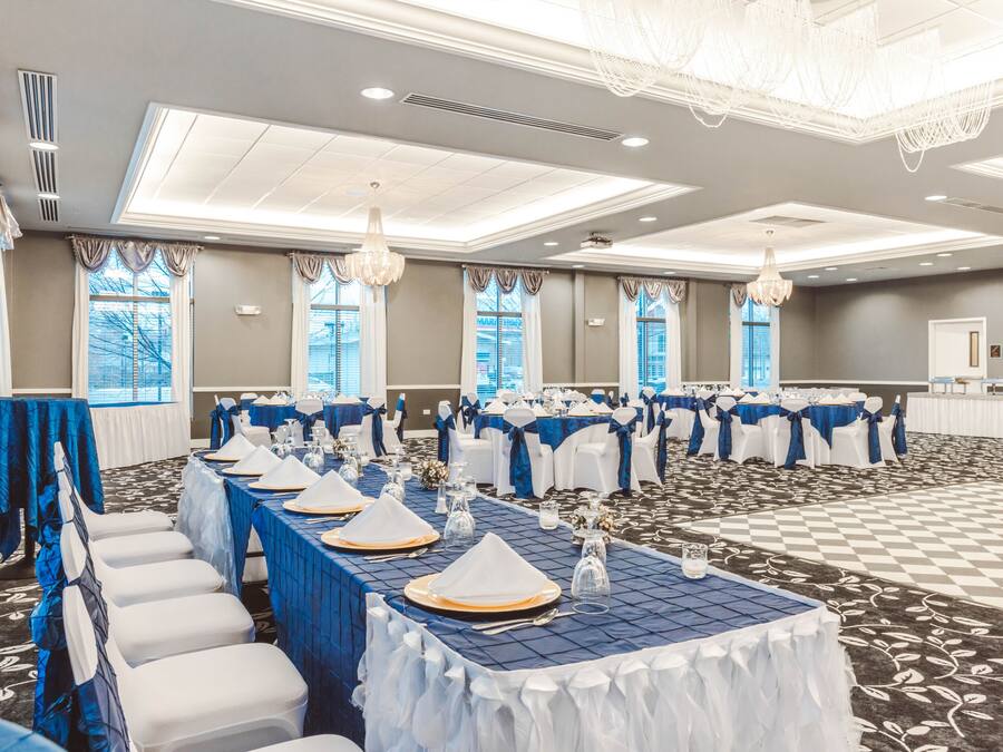 A banquet hall with tables set for events, featuring a checkered floor and large windows.
