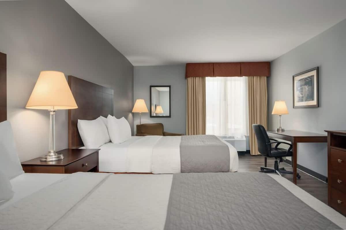 A hotel room with a large bed, two bedside lamps, a desk, and a chair.