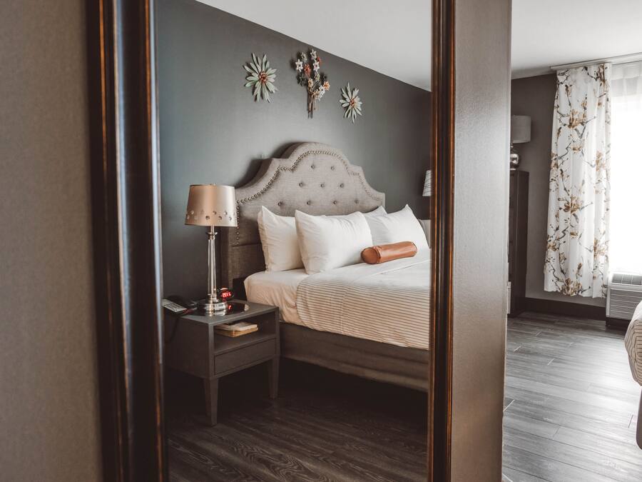 Una habitación de hotel con cama, mesita de noche, lámpara y un reloj en la pared.