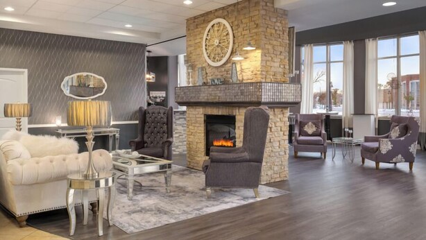 A spacious living room with a stone fireplace, leather sofas, and a modern chandelier.