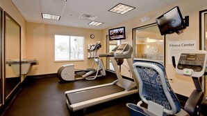 Un gimnasio con cintas de correr, elípticas y una bicicleta estática.
