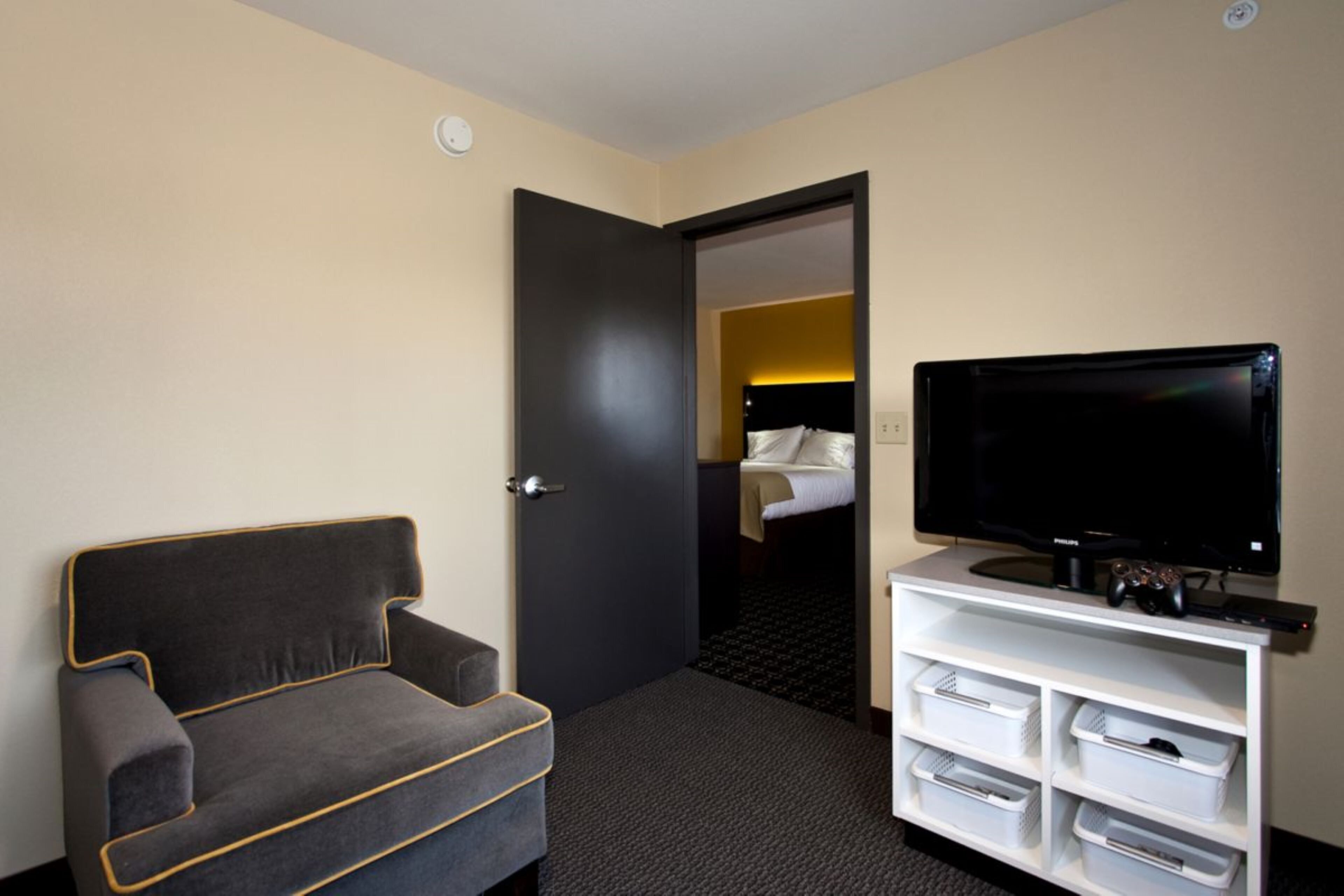 Ett hotellrum med en soffa, en tv och förvaringslådor.