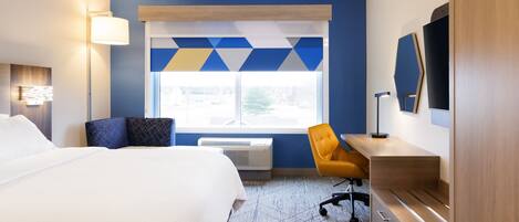 A hotel room with a large bed, a desk, a chair, a window with a view, and a TV on the wall.