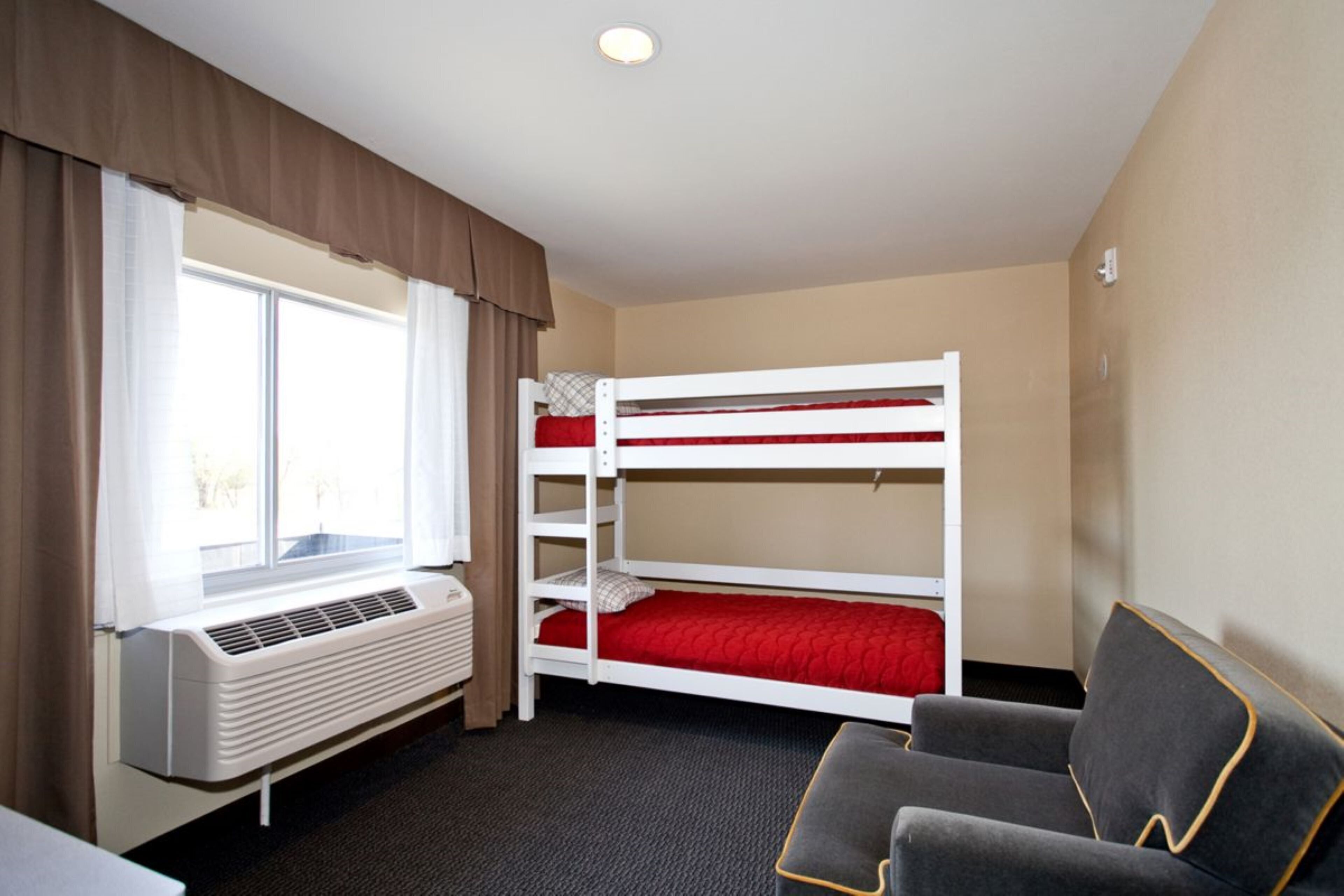 A room with a bunk bed, a heater, a window with curtains, and a couch.
