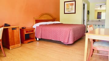 A hotel room with a wooden bed, a desk with a telephone, a chair, and a small table.