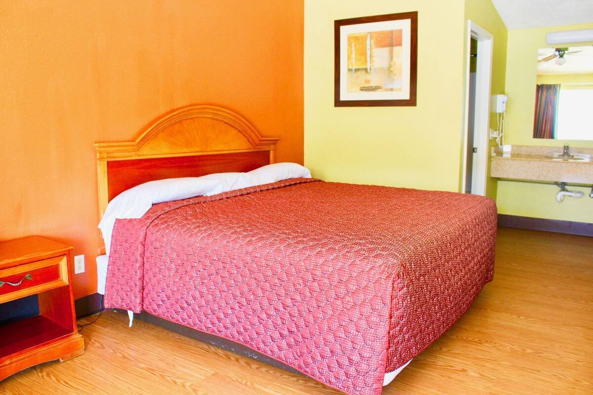 Uma cama de solteiro com cabeceira de madeira, uma mesa de cabeceira e um quadro na parede.