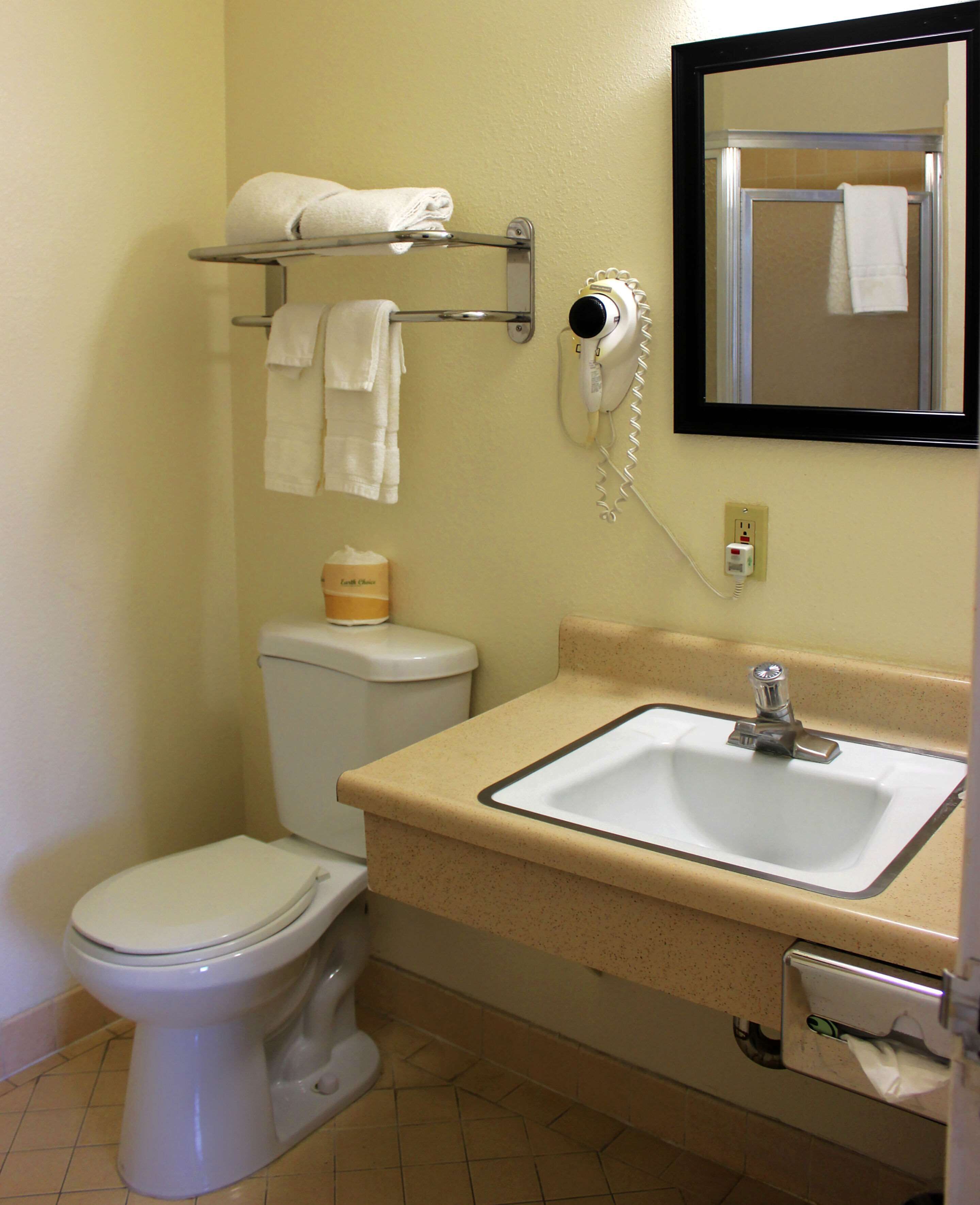 A bathroom with a toilet, sink, and a towel rack with towels.
