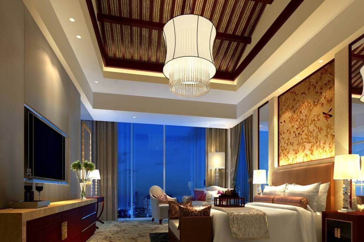 A modern hotel room with a large bed, a desk, a TV, and a view of the cityscape.