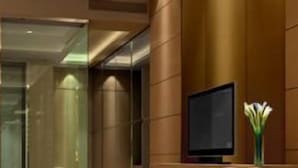 Un vestíbulo de hotel con una recepción, un televisor y un jarrón decorativo.