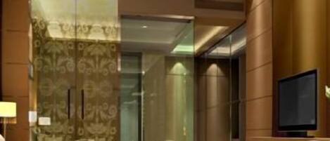A hotel lobby with a reception desk, a television, and a decorative vase.