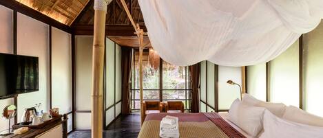 Una habitación con una cama, televisión, escritorio y ventana con vistas a zonas verdes.