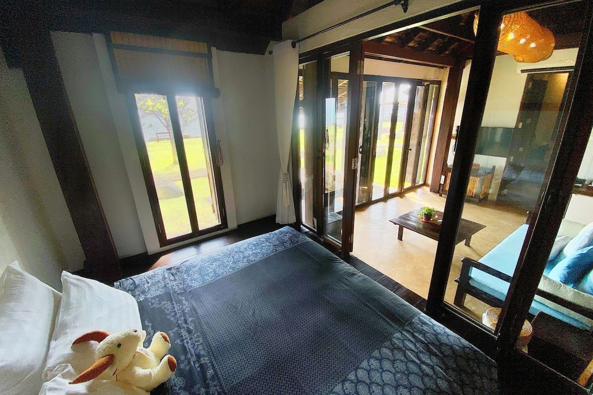 Een slaapkamer met een bed, een raam en uitzicht op buiten.