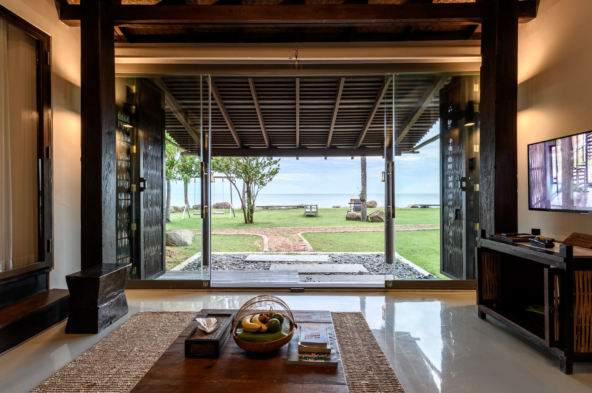 Un interior moderno con un gran ventanal que da a un patio con vistas al océano.