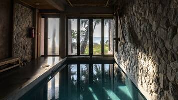 Una piscina con paredes de piedra y vista al océano.