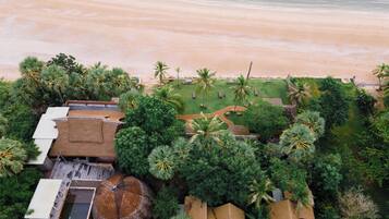 Vista aérea de un resort con playa, palmeras y zona de piscina.