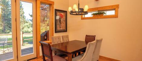 Un coin repas avec une table et des chaises en bois, un lustre et une fenêtre donnant sur l’extérieur.
