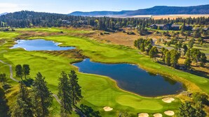 A golf course with multiple water bodies, surrounded by dense forests and distant hills. - Running Y Resort (Klamath Falls)