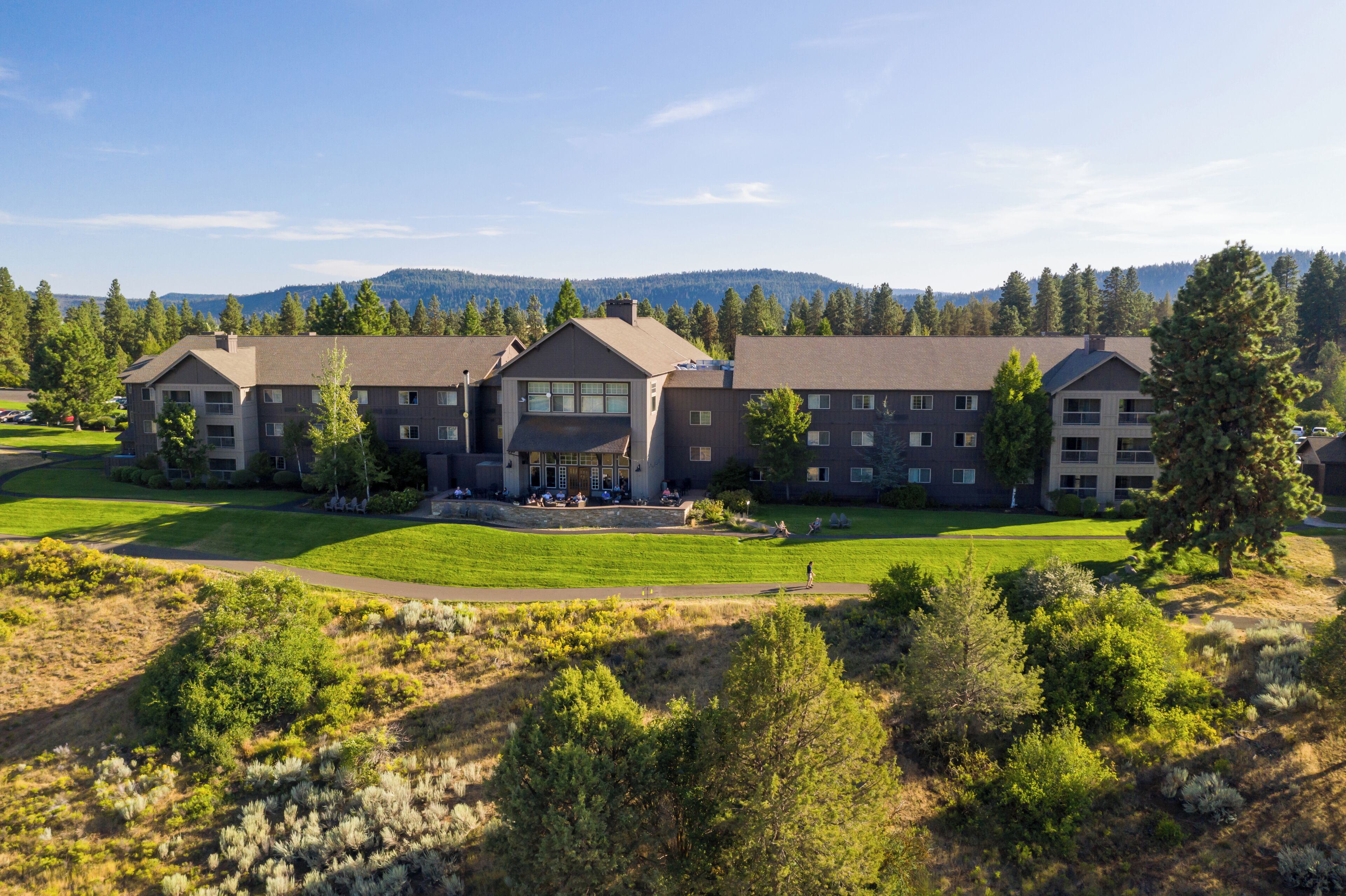 A multi-story hotel with a central courtyard, surrounded by greenery and a mountainous backdrop.